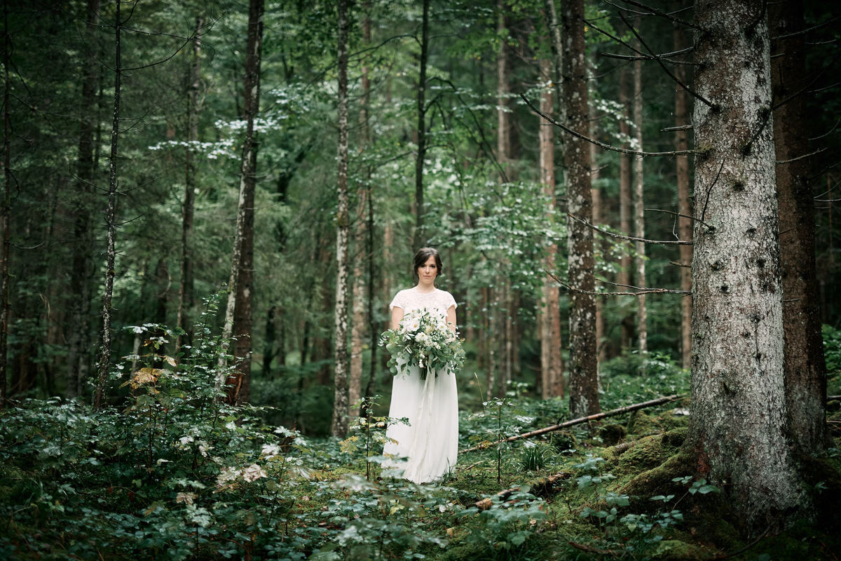 Braut im Wald hält Brautstrauß mit Eucalyptus für eien Sommerhochzeit